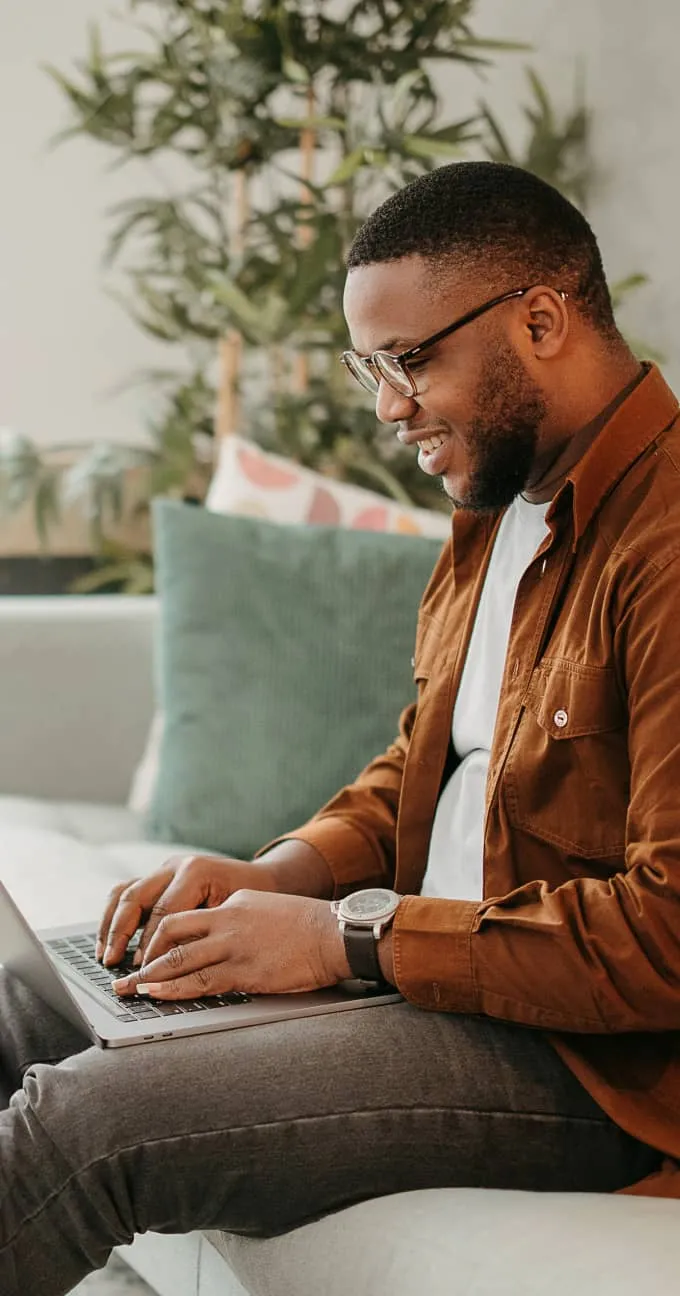 A man sitting on a couch and using his laptop