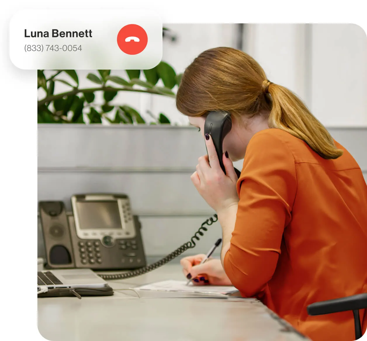 A female employee using a VoIP desk phone to take a phone call