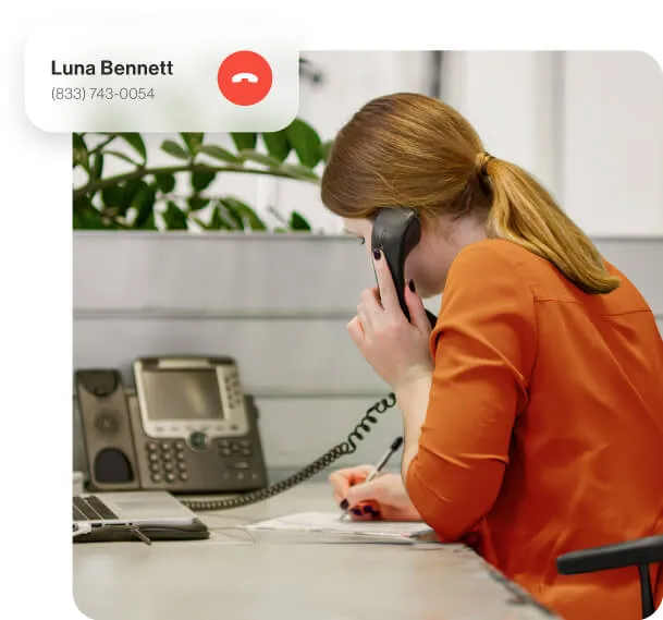 A female employee using a VoIP desk phone to take a phone call