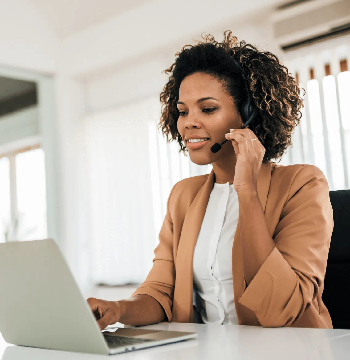 A female on a phone call using a headphone in front of a laptop