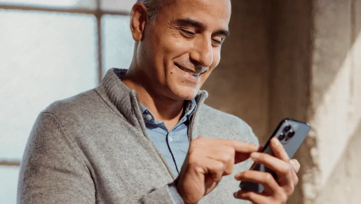 A man smiling while using his mobile phone